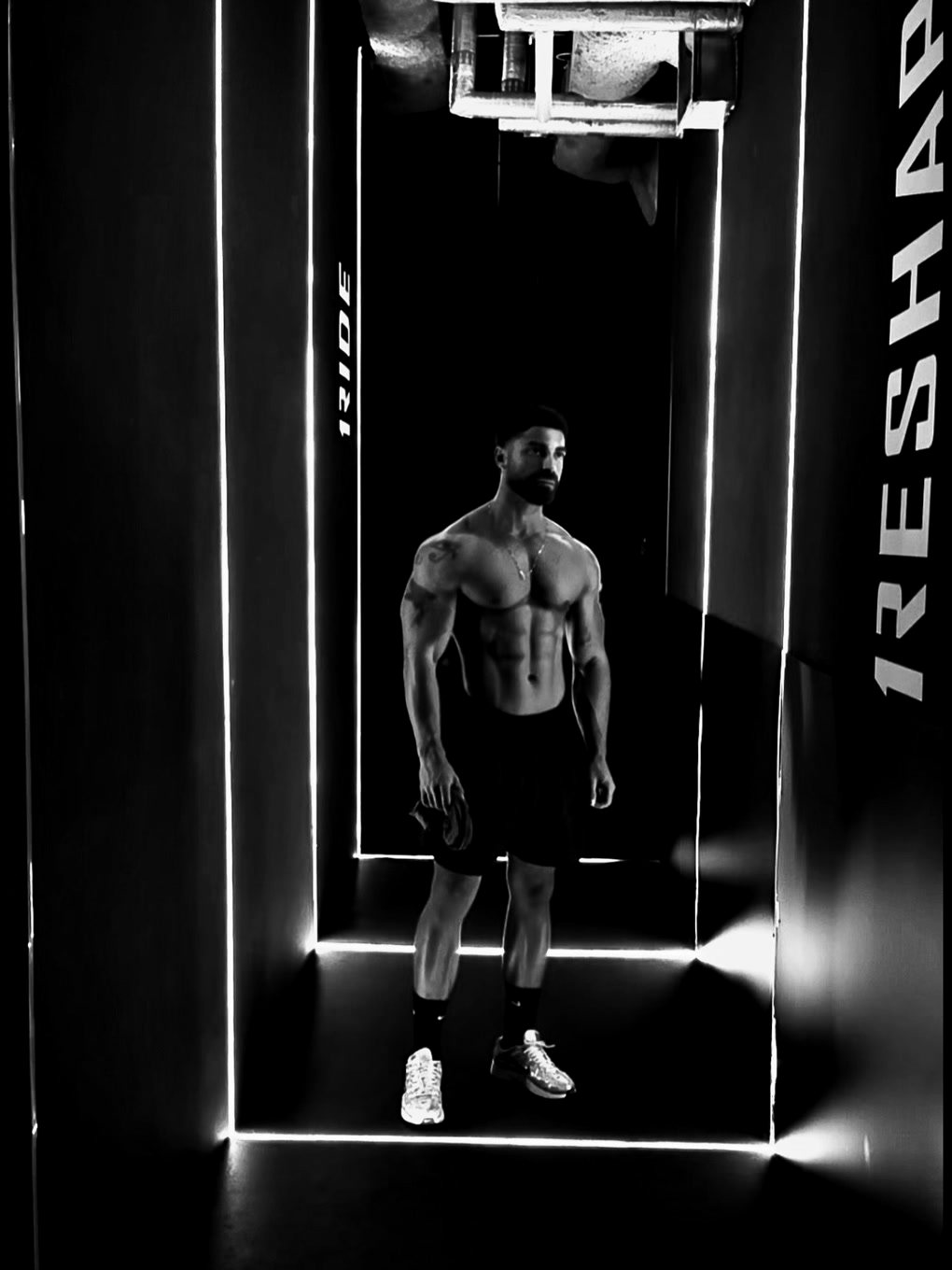 Giovanni Carlini in palestra, in piedi al centro di un corridoio illuminato da profili al neon